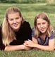 two sisters lying on grass share a moment of affection