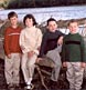 three brothers and their sister pose against a log