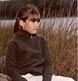 A young girl strikes a reflective pose at the waterside