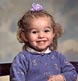 A young girl with bright smile shines with playful bow on head