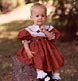 toddler girl in beautiful red dress shows a hint of curiosity